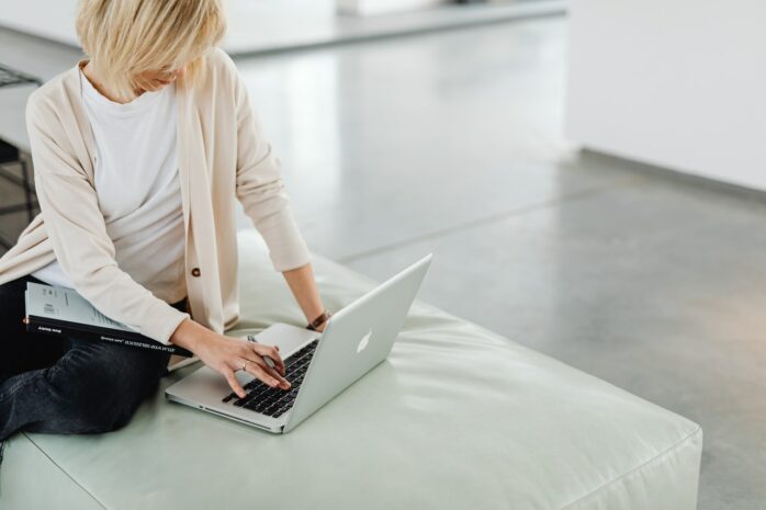Blonde woman on a bed using a laptop