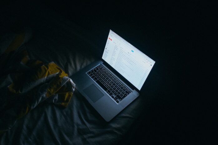 Laptop on a bed in a dark room