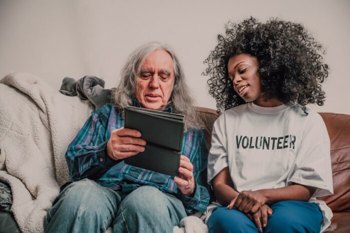 Volunteer woman with and old man looking at a tablet