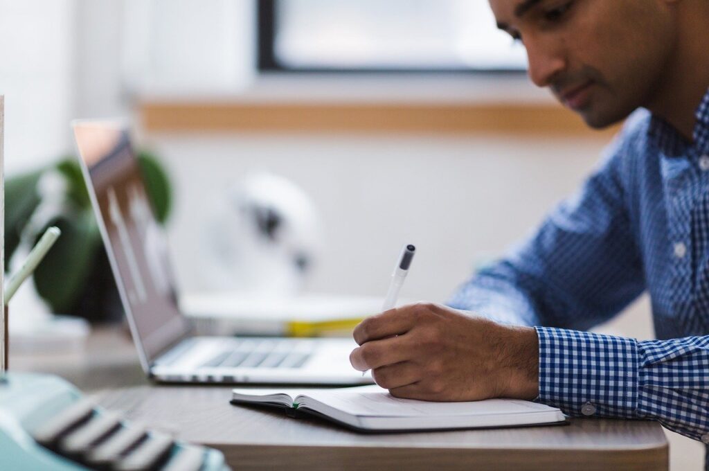 Man on a desk writing on a notebook
