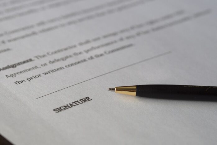 a pen lying on the dotted line where a signature goes