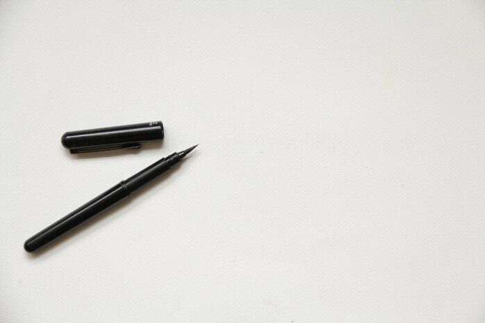 A white piece of paper with a pen lying on it, ready to be used for a signature